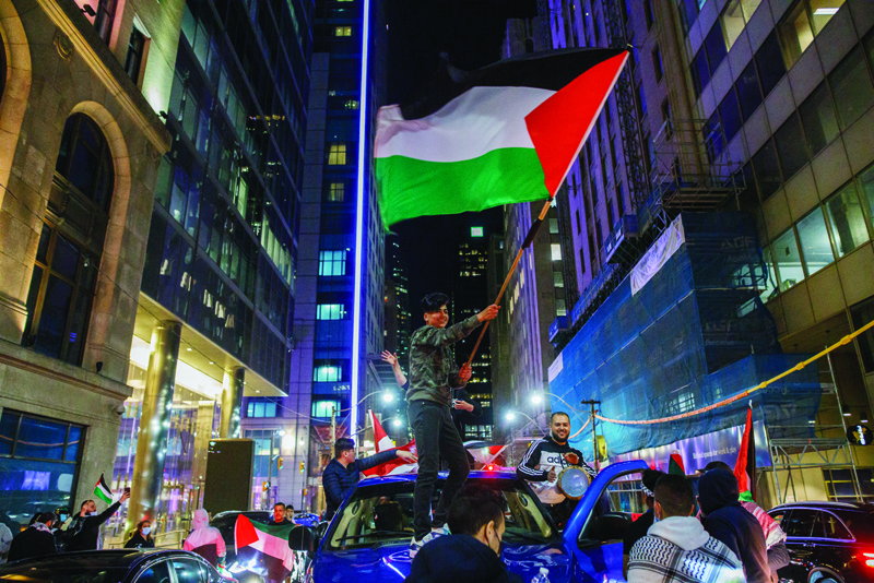 People wave flags atop cars in traffic during a demonstration to voice support for the people of Palestine at Toronto City Hall in Toronto on Saturday. nn