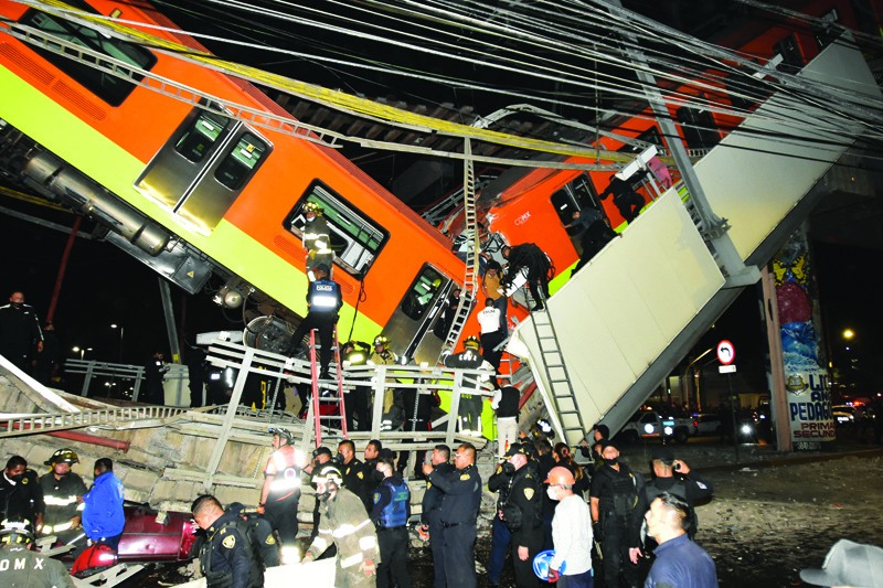 MEXICO CITY: Rescue workers gather at the site of a metro train accident after an overpass for a metro partially collapsed in Mexico City Monday. - AFPn