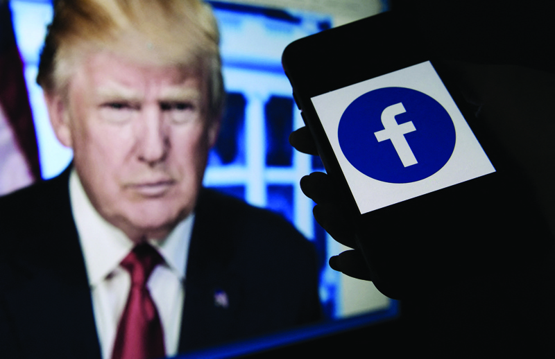 In this photo illustration, a phone screen displays a Facebook logo with the official portrait of former US President Donald Trump on the background, on Tuesday in Arlington, Virginia. - AFPn