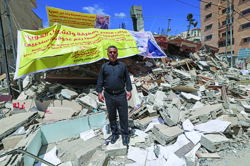 Samir Mansour, Palestinian owner of the eponymous bookstore and publishing house which had the largest collection of English literature in Gaza, poses on the rubble of the bookshop after it was destroyed by Zionist state air strikes, in Gaza City.-AFPn