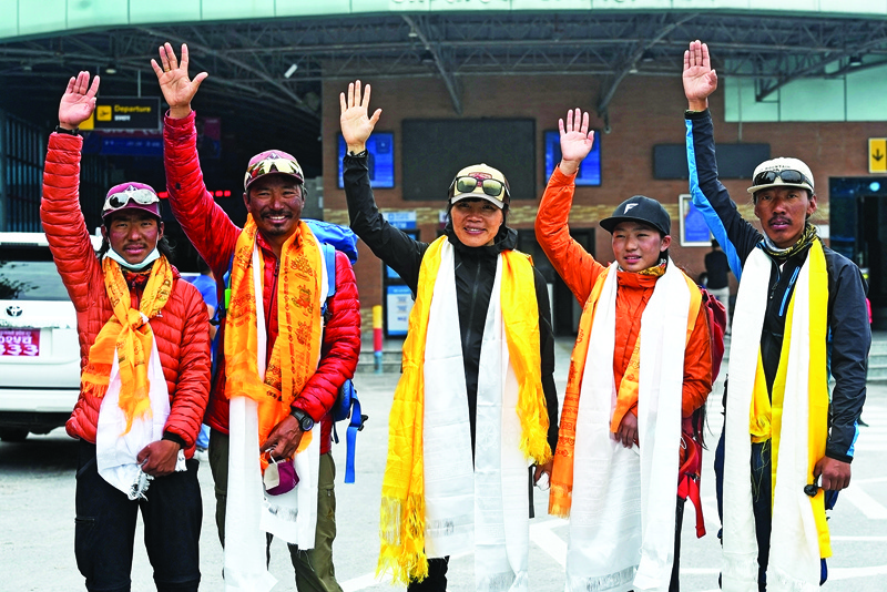 Hong Kong mountaineer Tsang Yin-hung (center), who recorded the world's fastest ascent of Mount Everest (8,848.86-metre) by a woman in 25 hours and 50 minutes, gestures while posing for pictures along with mountaineers Pemba Dorje Sherpa (second left), Phurba Thiley Sherpa (left), Nima Lhamu Sherpa (second right) and Phurba Tenjing Sherpa (right) as they arrive at an airport in Kathmandu yesterday. — AFP photosn