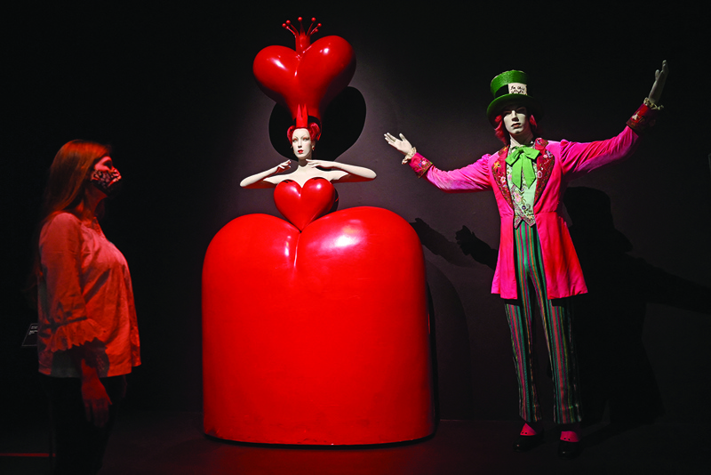 A museum employee poses next to a costume entitled (left) ‘ Queen of Hearts costume‘ and ‘Costume for the Mad Hatter’ 2010 by artist Bob Crowley during a press preview of the exhibition Alice: Curiouser and Curiouser at the Victoria & Albert museum in London. — AFP photosn