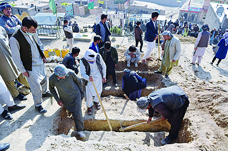 KABUL: Mourners and relatives dig graves for girls, who died in Saturday's multiple blasts outside a girls' school, during the burial at a desolate hilltop cemetery in Dasht-e-Barchi on the outskirts of Kabul yesterday.-AFPn