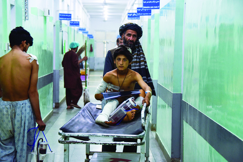 KANDAHAR: A man pushes an injured boy on a stretcher along a hospital corridor in Kandahar yesterday as he receives medical treatment after being hurt by a roadside bomb that struck a bus overnight killing at least 11 people. -- AFPn