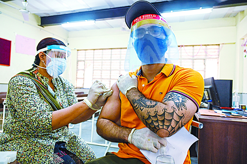 NEW DELHI: A health worker inoculates a man with a dose of the Covaxin COVID-19 coronavirus vaccine in a school-turned-vaccination center yesterday. - AFP n