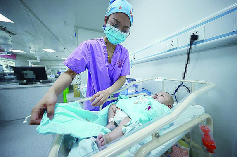 DANZHAI, China: A medical staff member takes care of a newborn baby at a hospital in China's southwestern Guizhou province yesterday. - AFP n
