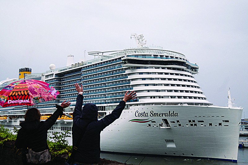 SAVONA, Italy: Pedestrians waves at the Costa Smeralda cruise ship as it leaves on Saturday. - AFP n