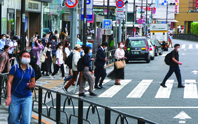TOKYO: Pedestrians cross a street in Tokyo yesterday as Japan's economy contracted 1.3 percent in the three months to March after the government reimposed coronavirus restrictions in major cities as infections surged, data showed. -AFPn
