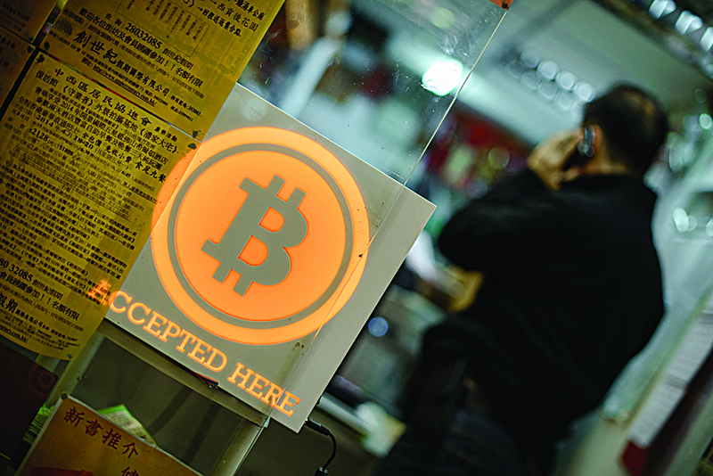 In this file photograph, a man talking on a mobile phone in a shop displaying a bitcoin sign during the opening ceremony of the first bitcoin retail shop in Hong Kong. - AFPnnnnIn this file photograph, a man talking on a mobile phone in a shop displaying a bitcoin sign during the opening ceremony of the first bitcoin retail shop in Hong Kong. - AFPn