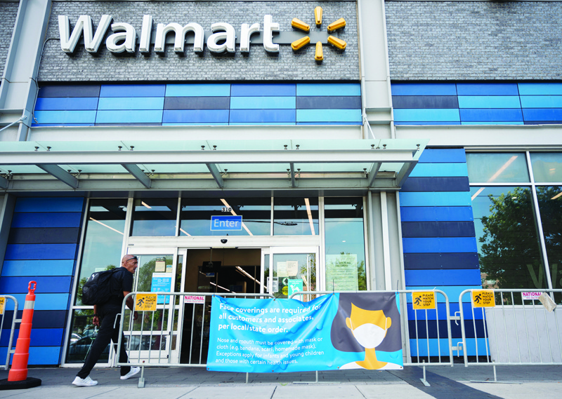 In this file photo taken on July 15, 2020 a man walks near a sign informing customers that face coverings are required in front of a Walmart store in Washington, DC. US retail giant Walmart on May 14 said customers who are fully vaccinated against Covid-19 no longer have to wear masks in their stores, and staff can do the same starting next ween