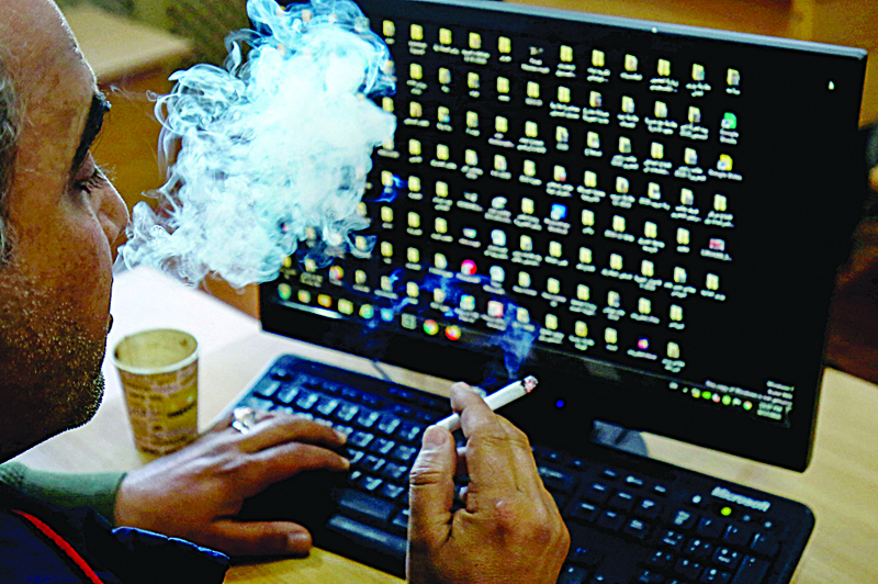 AMMAN: A Jordanian man smokes a cigarette as he checks his computer on March 26, 2021. - AFP n