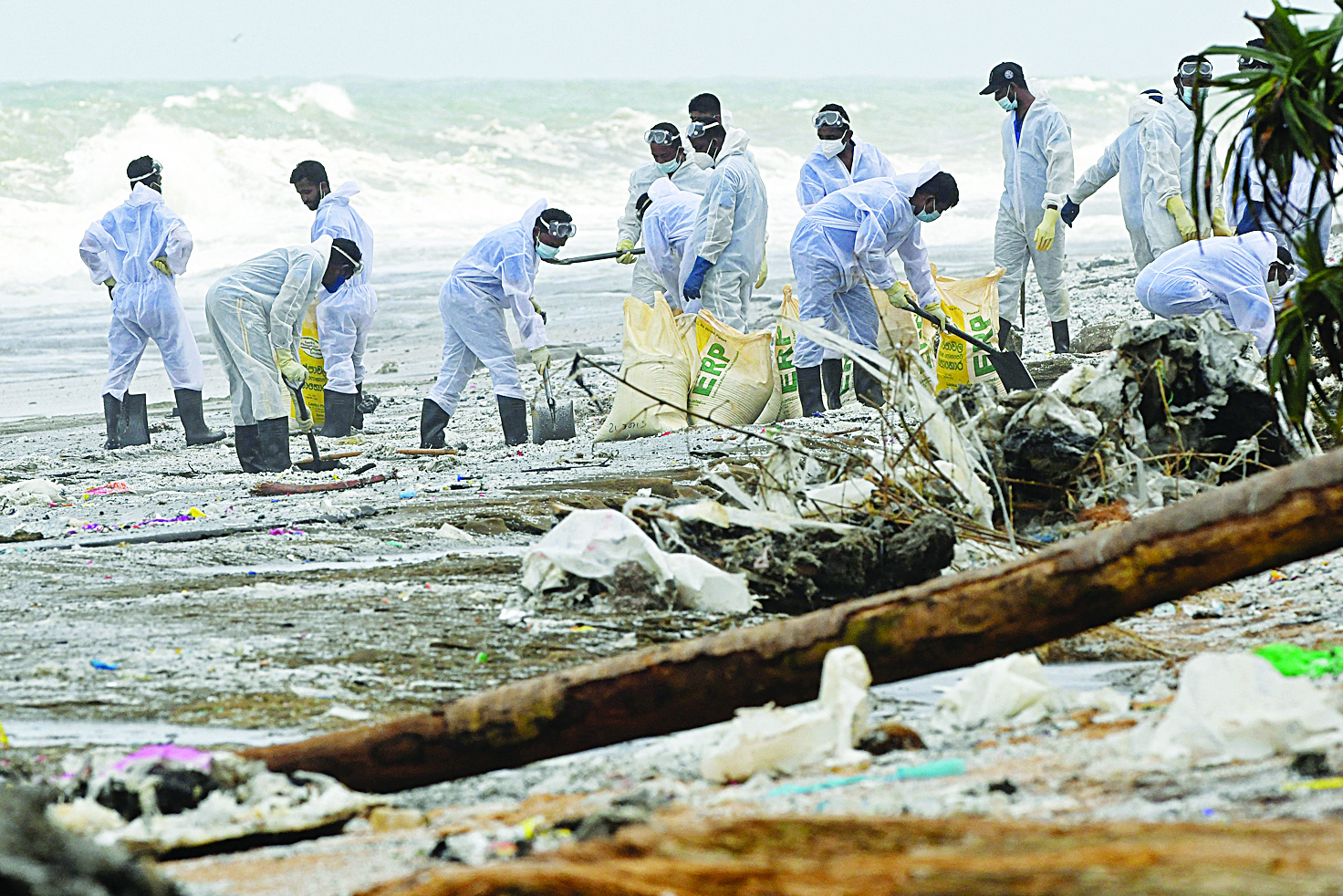 COLOMBO: Members of the Sri Lankan navy remove debris washed ashore from the Singapore-registered container ship MV X-Press Pearl on a beach yesterday. —AFP