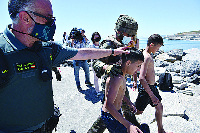 Spanish soldiers and Guardia Civil members assist migrant minors after they arrived swimming to the Spanish enclave of Ceuta, yesterday.-AFPn