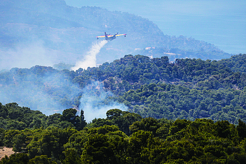 MAVROLIMNI, GREECE: A firefighting airplane sprays water to extinguish a wild fire on Mount Geraneia, west of Athens yesterday.-AFP n