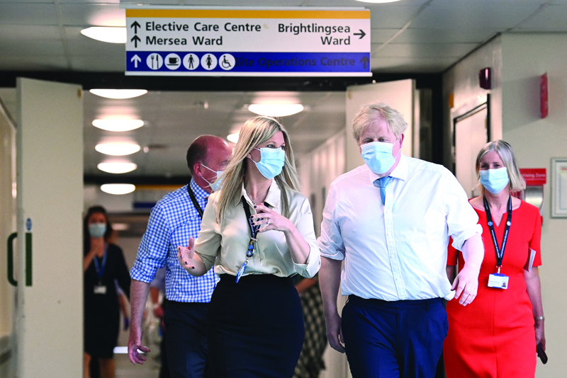Britain's Prime Minister Boris Johnson (right) flanked by Alison Power, Director of Operations visits Colchester hospital in Colchester, eastern England yesterday.-AFPn