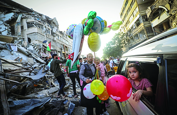 GAZA: A Palestinian man sells balloons in front of the destroyed Al-Shuruq building on Friday. — AFP