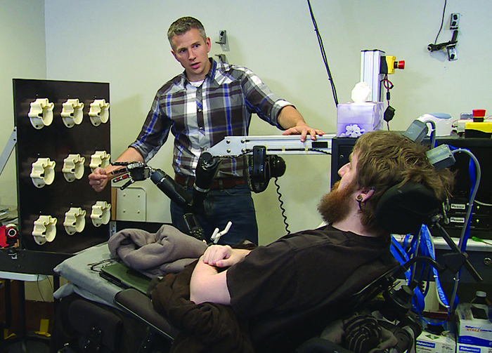This undated handout photo shows Nathan Copeland, who is quadriplegic, controlling a robotic arm, and Rob Gaunt, assistant professor in the Department of Physical Medicine and Rehabilitation at the University of Pittsburgh. - AFP