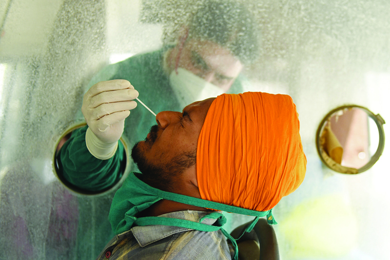 AMRITSAR: A health worker collects a nasal swab sample from a man to test for COVID-19 in a mobile testing van yesterday. - AFP  n