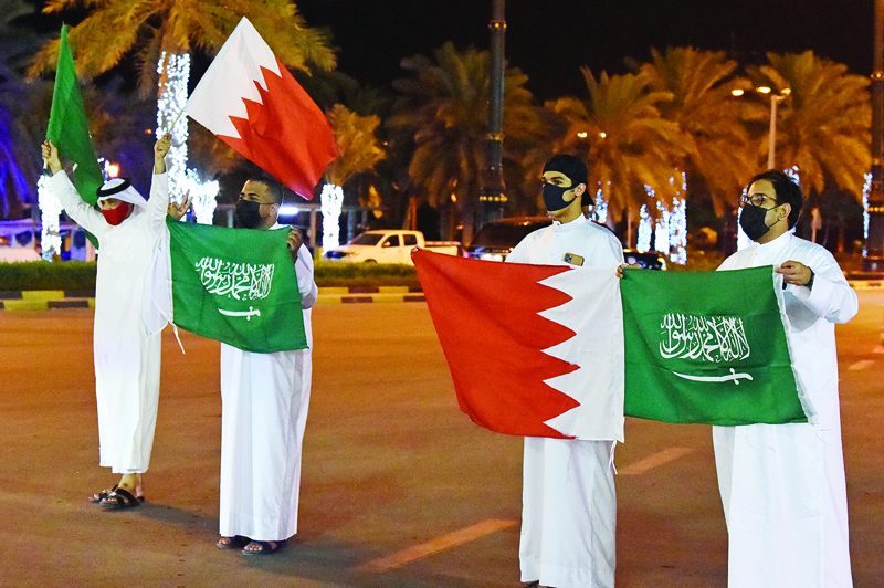 Bahrain men welcome Saudi travelers with Saudi and Bahraini flags on King Fahad Causeway yesterday. - AFP n
