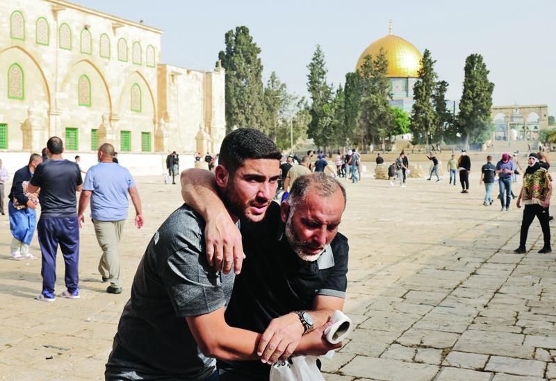 JERUSALEM: A Palestinian man helps a wounded fellow Palestinian after being attacked by Zionist security forces at Jerusalem's Al-Aqsa mosque compound yesterday. - AFPnn