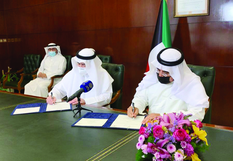 KUWAIT: NCCAL's Secretary General Kamel Al-Abduljaleel (left) and Kuwait Writers Association's Secretary General Dr Khaled Ramadan sign the agreement. - KUNAn