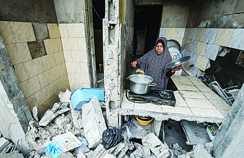 GAZA CITY: A Palestinian woman who has returned to her neighborhood, cooks a meal in what remains of her home, hit by Zionist entity’s bombardment in Gaza City on Friday. - AFPnn