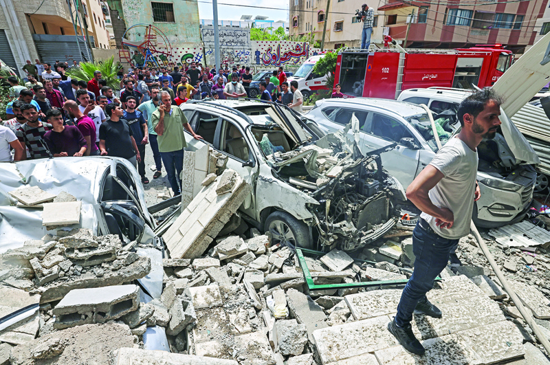 GAZA: Palestinians inspect a site hit during a Zionist airstrike in Gaza City yesterday. - AFP n