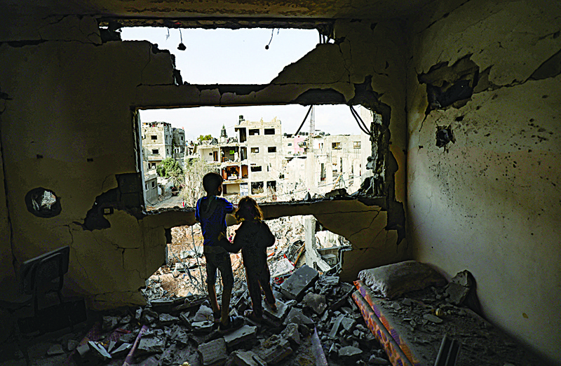 GAZA CITY: Palestinian children who have returned to their neighborhood, stare at the damaged from their home, hit by Zionist entity’s bombardment in Gaza City, after a ceasefire brokered by Egypt between Zionist and Hamas, on Friday. - AFPnn