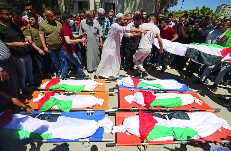 GAZA CITY: Palestinian mourners gather around bodies of members of the Abu Hatab and Al-Hadidi families during a funeral procession in Gaza city. - AFPn