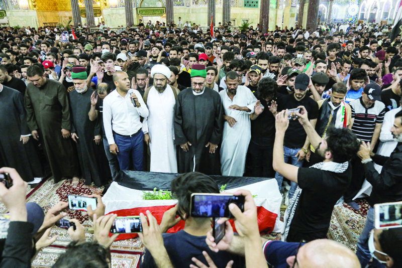KARBALA: Mourners pray by the body of Iraqi anti-government activist Ihab Al-Wazni (Ehab Al-Ouazni) during his funeral at the Imam Hussein Shrine in the central holy shrine city of Karbala Sunday.-AFPn