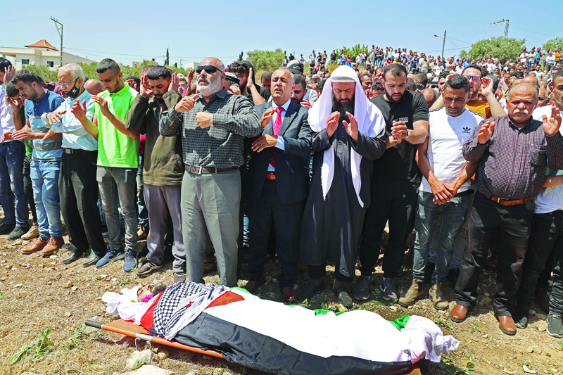 GAZA CITY: Palestinians pray over the body of 23-year-old Palestinian Muntaser Jawabreh, who succumbed to his injuries after being wounded two days ago in clashes with Zionist troops during protests against the ongoing airstrikes on Gaza, at his funeral in the village of Oum Dar east of Jenin in the occupied West Bank yesterday.—AFPn