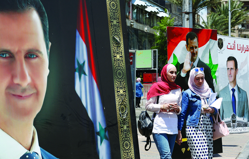 DAMASCUS: People walk next to election campaign billboards depicting Syrian President Bashar Al-Assad, a candidate for the upcoming presidential vote, in the capital Damascus, yesterday. - AFPn