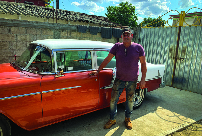 Panel beater Pedro Manso poses in front of a Chevrolet BelAir 55 car rebuilt by him in his workshop in the town of Placetas, Villa Clara province, central Cuba, April 24, 2021. – AFP 