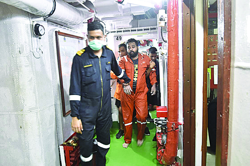 Naval personnel from INS Kolkata are seen escorting a rescued crew members from the sea after they were washed away from a barge which had gone adrift amidst heavy rain and strong winds of cyclonic storm Taukta. - AFPnn