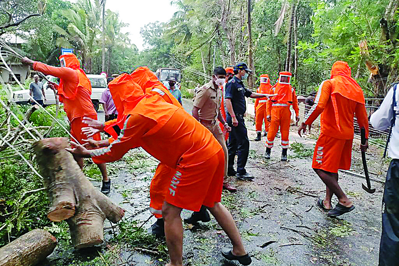 This handout photo released yesterday by the National Disaster Response Force (NDRF) shows National Disaster Response Force (NDRF) personnel clearing fallen trees from a road following severe cyclonic storm 'Tauktae' at Margao in Goa. - AFPn