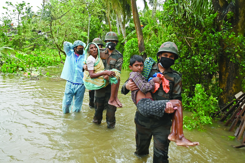DIGHA, India: Indian army personnel wades through the flooded village roads carrying people to safety as Cyclone Yaas barrels towards India's eastern coast in the Bay of Bengal. — AFP n