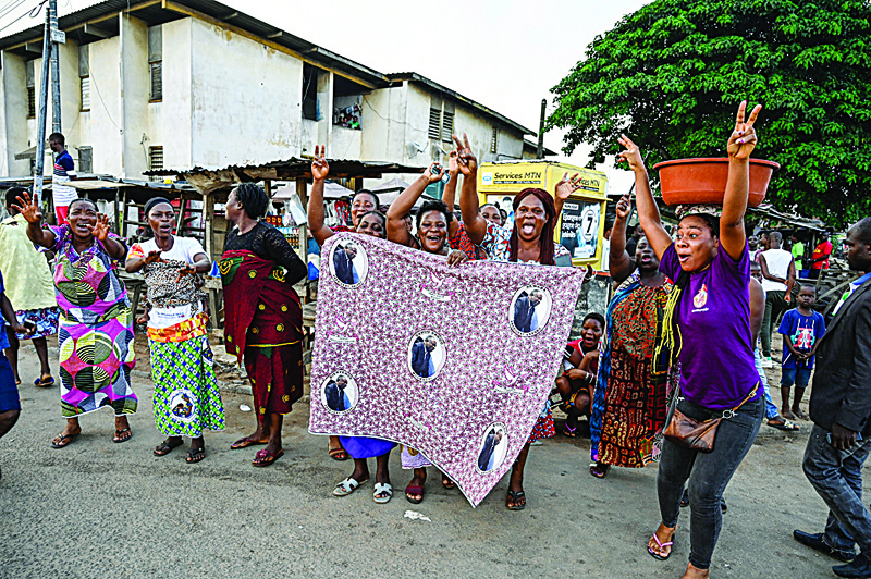ABIDJAN: Women gesture as they hold a cloth bearing the face of former Ivory Coast President Laurent Gbagbo in Yopougon, a popular district of Abidjan, yesterday. - AFPnnn