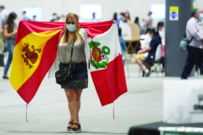 MADRID: A Peruvian resident walks with Spanish and Peruvian flags after casting her vote for the presidential election runoff in a polling station at the Ifema congress center in Madrid yesterday. - AFPnnn