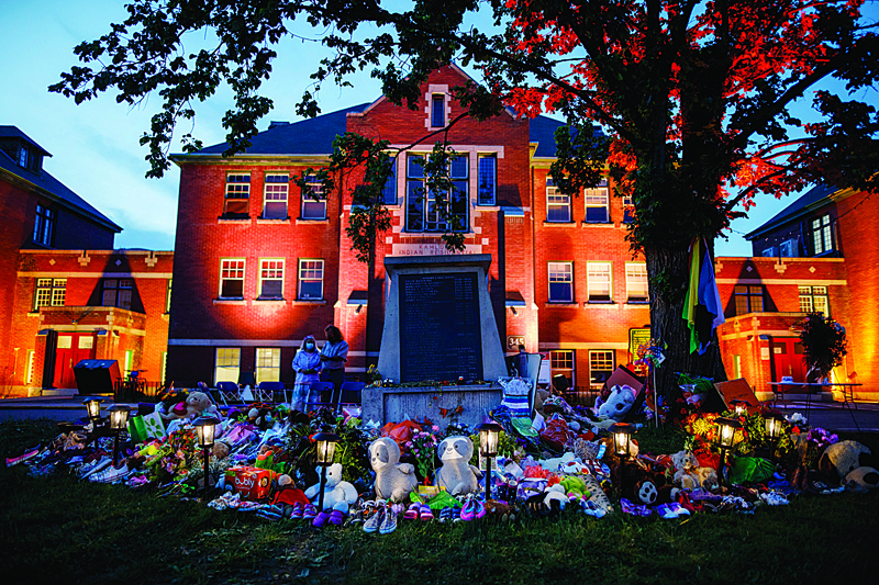 KAMLOOPS, Canada: A makeshift memorial to honour the 215 children whose remains have been discovered buried near the facility is seen as orange light drapes the facade of the former Kamloops Indian Residential School in Kamloops, British Columbia. - AFPnn