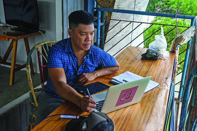 This photo taken on June 2, 2021 shows digital nomad, Carlo Almendral, the chief executive of an artificial intelligence startup, browsing his laptop at a beachfront resort in the town of San Juan. n
