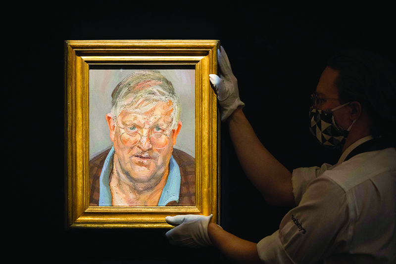 In this file photo a gallery worker poses with a painting titled ‘David Hockney’ by British painter Lucian Freud during a photocall at Sotheby's auction house in central London. — AFP n