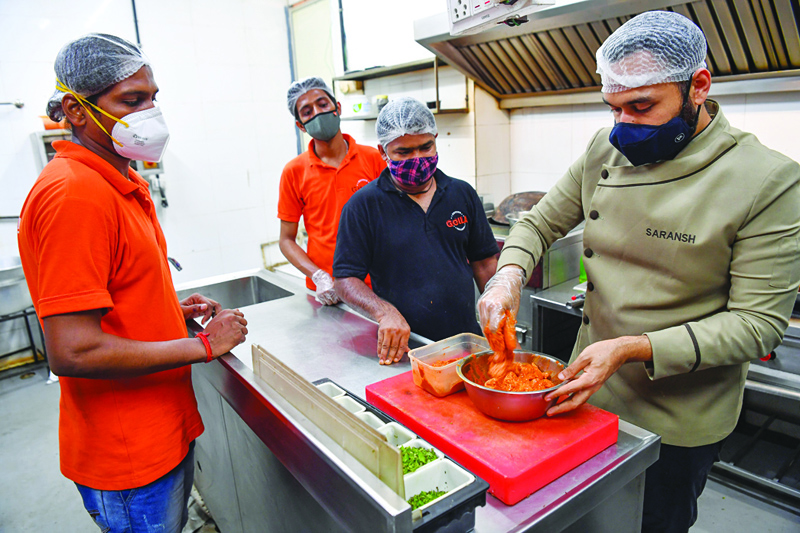 Staff watch chef Saransh Goila (right) marinating chicken with spices in the kitchen of the Goila Butter Chicken restaurant in Mumbai. - AFP photosn