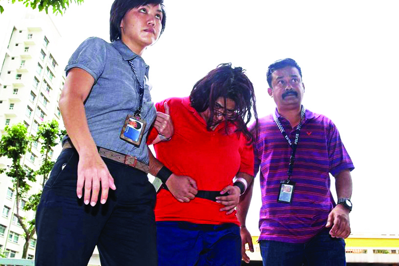 SINGAPORE: File photo provided by The Straits Times taken on August 3, 2016 and received by AFP yesterday shows police officers escorting Gaiyathiri Murugayan (C) to her home for investigations into a case involving the starvation and death of her domestic worker in Singapore. – AFPnn