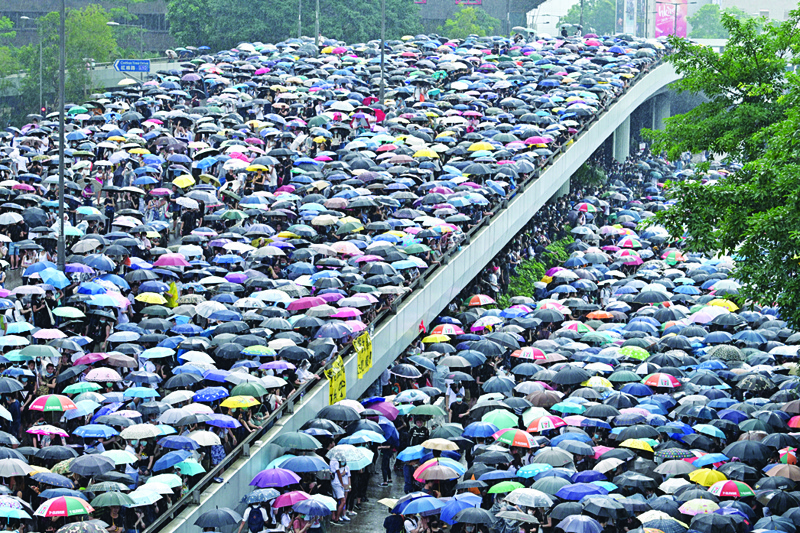 HONG KONG: In this file photo taken on June 12, 2019, protesters shelter under umbrellas during a downpour as they occupy roads near the government headquarters in Hong Kong. - AFPn