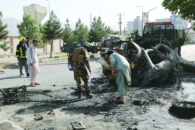 KABUL: Afghan security forces inspect the remains of a vehicle at the site of a bomb blast in Kabul yesterday. - AFPn