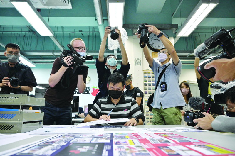 HONG KONG: Members of the press take photos as executive editor in chief Lam Man-Chung (C) proof reads the next day's 'Apple Daily' newspaper before it goes to print for what was announced earlier in the day to be for the last time, in Hong Kong late yesterday. - AFPnnn