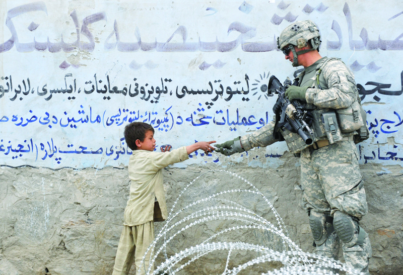NANGARHAR: In this file photo a US soldier from 4th Infantry Division 4 Brigade Alpha Company presents a gift to an Afghan child during a patrol at Khogyani in Nangarhar. The US pullout from Afghanistan is at least 16 percent and as much as a quarter complete, the Pentagon's Central Command said. - AFPnnn