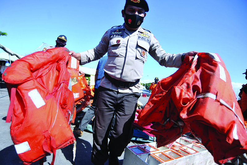 BALI: A rescuer shows off life jackets recovered from the sea on June 30, 2021, after the KMP Yunicee, a passenger ferry carrying 57 passengers and crew, sank off the coast of Bali island, killing at least seven. - AFPn