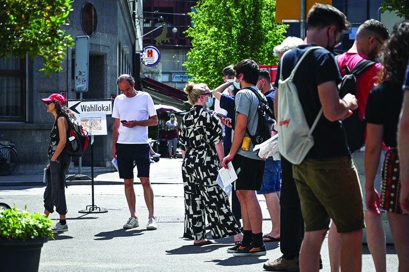 BASEL: People queue at a ballot station yesterday in Basel as Switzerland votes a series of hot topics: anti-terror measures, COVID-19 laws and proposals to protect the environment through banning synthetic pesticides. – AFPn