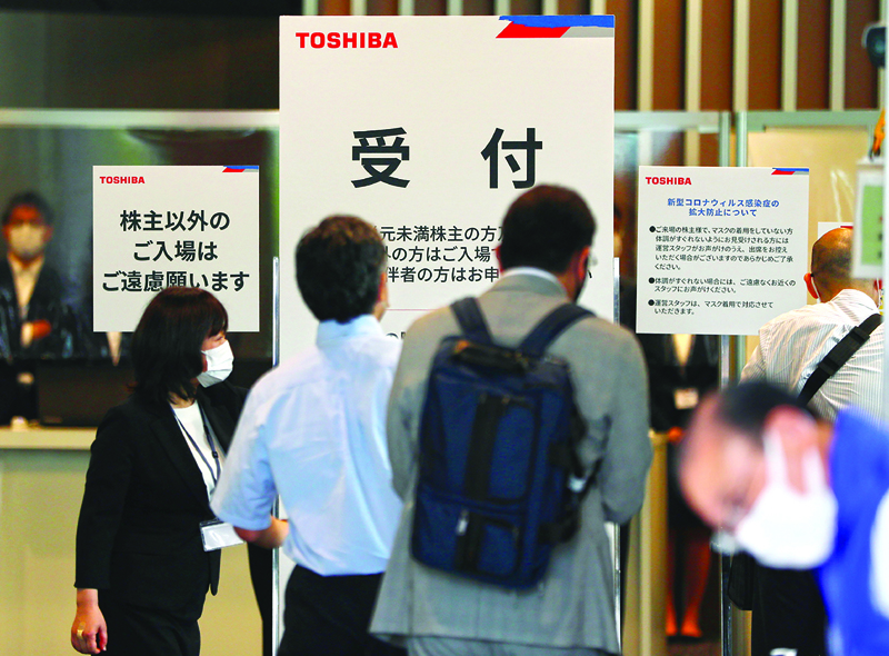 TOKYO: A staff (left) guides shareholders to attend Toshiba annual general meeting of its shareholders in Tokyo Friday. – AFPn
